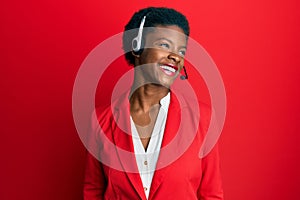 Young african american girl wearing call center agent headset looking away to side with smile on face, natural expression