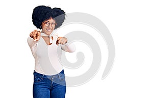 Young african american girl wearing casual clothes and glasses pointing to you and the camera with fingers, smiling positive and