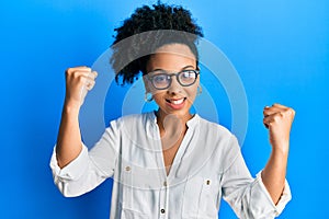 Young african american girl wearing casual clothes and glasses screaming proud, celebrating victory and success very excited with