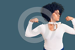 Young african american girl wearing casual clothes and glasses showing arms muscles smiling proud