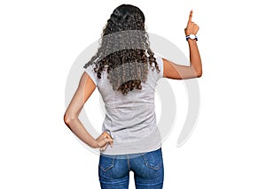 Young african american girl wearing casual clothes posing backwards pointing ahead with finger hand