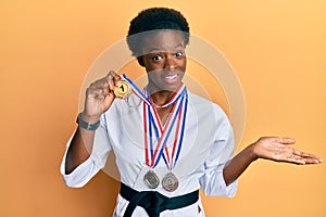 Young african american girl wearing karate kimono and black belt celebrating achievement with happy smile and winner expression