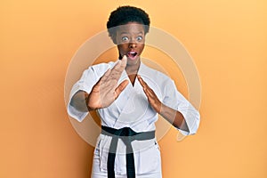 Young african american girl wearing karate kimono and black belt celebrating crazy and amazed for success with open eyes screaming