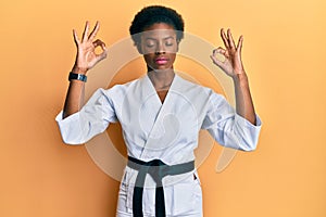 Young african american girl wearing karate kimono and black belt relax and smiling with eyes closed doing meditation gesture with