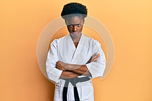 Young african american girl wearing karate kimono and black belt skeptic and nervous, disapproving expression on face with crossed