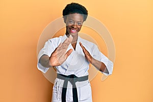 Young african american girl wearing karate kimono and black belt smiling with a happy and cool smile on face