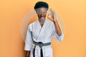 Young african american girl wearing karate kimono and black belt smiling positive doing ok sign with hand and fingers