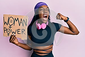 Young african american girl wearing sportswear holding woman power banner angry and mad screaming frustrated and furious, shouting