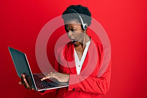 Young african american girl working at the office wearing operator headset angry and mad screaming frustrated and furious,