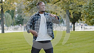 Young African American guy handsome man in headphones with mobile phone listening to music online enjoying audio song