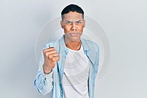 Young african american guy wearing casual clothes angry and mad raising fist frustrated and furious while shouting with anger