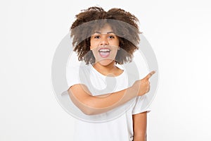 Young african american happy woman showing copyspace pointing on isolated white background. Afro hair. Template, blank shirt.