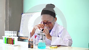 Young African American kid using microscope in lab