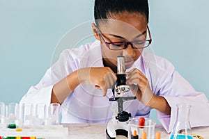 Young African American kid using microscope in lab