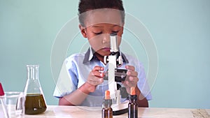 Young African American kid using microscope in lab