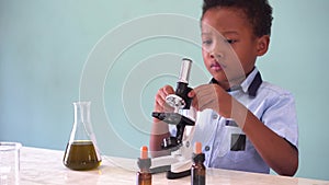 Young African American kid using microscope in lab