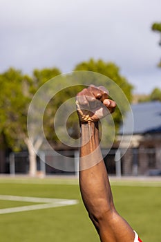 A young African American male athlete raises clenched fist high, copy space