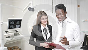 Young African American male doctor dentist and Beautiful girl patient in dental clinic. Medicine, health, stomatology