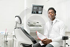 Young African American male doctor dentist in dental office. Medicine, health, stomatology concept. Looking into the