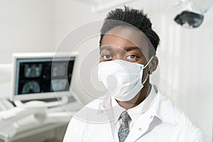 Young African American male doctor dentist in a medical mask. Medicine, health, stomatology concept. Looking into the