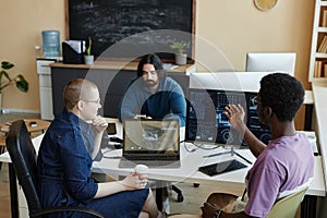 Young African American male IT engineer explaining something to female colleague