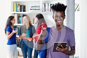 Young african american male student with tablet computer with group of multi ethnic college students