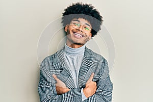 Young african american man with afro hair wearing casual clothes  glasses happy face smiling with crossed arms looking at the