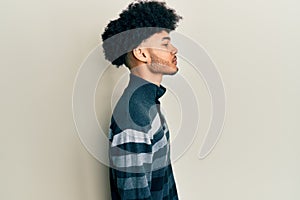 Young african american man with afro hair wearing casual clothes looking to side, relax profile pose with natural face with