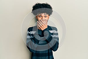 Young african american man with afro hair wearing casual clothes shocked covering mouth with hands for mistake