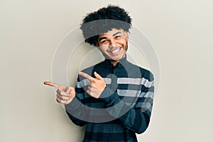 Young african american man with afro hair wearing casual clothes smiling and looking at the camera pointing with two hands and