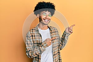 Young african american man with afro hair wearing casual clothes smiling and looking at the camera pointing with two hands and