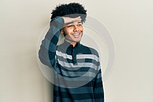 Young african american man with afro hair wearing casual clothes very happy and smiling looking far away with hand over head