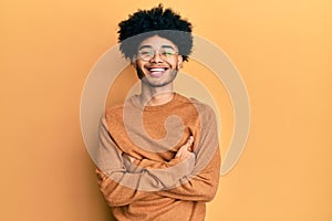 Young african american man with afro hair wearing casual winter sweater happy face smiling with crossed arms looking at the camera