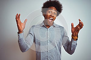 Young african american man with afro hair wearing grey shirt over isolated white background celebrating mad and crazy for success