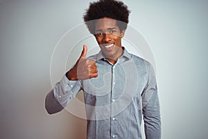Young african american man with afro hair wearing grey shirt over isolated white background doing happy thumbs up gesture with