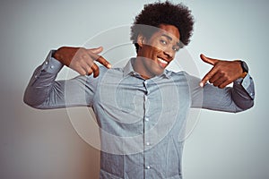 Young african american man with afro hair wearing grey shirt over isolated white background looking confident with smile on face,