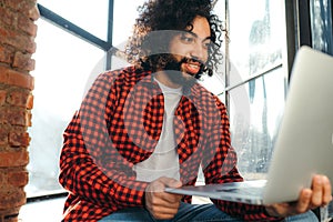 Young african american man with afro hairstyle works at the computer against the background of windows