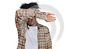 Young african american man with beard wearing casual clothes and glasses covering eyes with arm, looking serious and sad