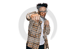 Young african american man with beard wearing casual clothes and glasses punching fist to fight, aggressive and angry attack,