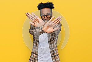 Young african american man with beard wearing casual clothes and glasses rejection expression crossing arms and palms doing