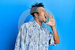 Young african american man with beard wearing casual clothes shouting and screaming loud to side with hand on mouth