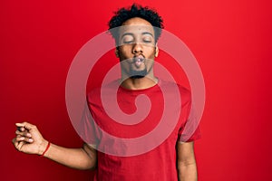 Young african american man with beard wearing casual red t shirt making fish face with lips, crazy and comical gesture