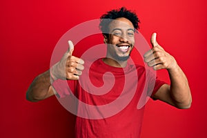 Young african american man with beard wearing casual red t shirt success sign doing positive gesture with hand, thumbs up smiling