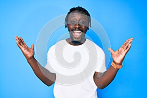 Young african american man with braids wearing casual white tshirt celebrating victory with happy smile and winner expression with