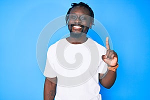 Young african american man with braids wearing casual white tshirt pointing finger up with successful idea