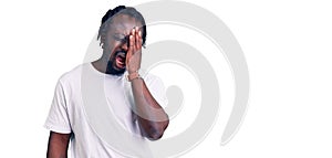 Young african american man with braids wearing casual white tshirt yawning tired covering half face, eye and mouth with hand
