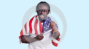 Young african american man with braids wearing united states flag annoyed and frustrated shouting with anger, yelling crazy with