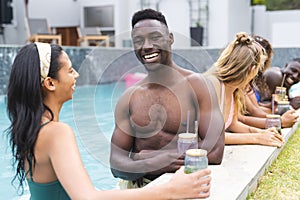 A young African American man with a bright smile is enjoying a poolside conversation