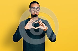 Young african american man doing heart symbol with hands puffing cheeks with funny face