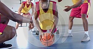 Young African American man doing push ups on a basketball in an indoor court